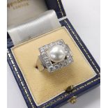 Attractive platinum diamond and cultured pearl dress ring, the 9.5mm white pearl in a surround of