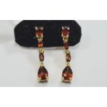 Mozambique Red Garnet Drop Earrings, a pear cut below two smaller marquise cuts, suspended from a