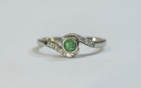 Silver Dress Ring set with a central Emerald between small round cut Diamonds.