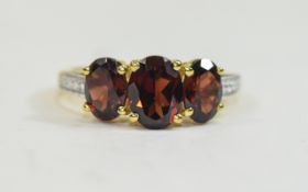 Mozambique Red Garnet Three Stone Ring, the centre oval cut stone of 1.5cts flanked by two further