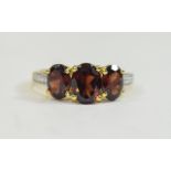 Mozambique Red Garnet Three Stone Ring, the centre oval cut stone of 1.5cts flanked by two further