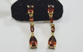 Mozambique Red Garnet Drop Earrings, a pear cut below two smaller marquise cuts, suspended from a