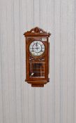 Light Wood Wall Mounted Clock Carved detail to casing, glazed front and sides to expose mechanism.
