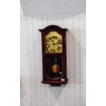 Clock Contemporary wall mounted clock in dark wood effect casing.