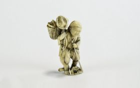 Ivory Figural Netsuke, showing a man walking along with a staff, carrying a creature in a basket