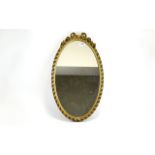 Mirror Oval mirror in dark gilt frame with central bow and floral moulding to top. Approx height 23.