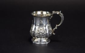 A Mid Victorian Period Embossed Silver Cup with Ornate Scroll Handle, Floral Decoration.