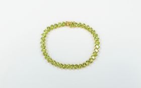 Peridot Tennis Bracelet, a single row of oval cut peridots, totalling 16cts, set, unusually,