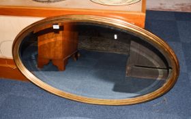 Oval Statement Mirror Large bevelled glass mirror of plain form in pale gilt classical style frame.