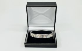 Silver Bangle Hinged bangle with floral and foliate engraving and safety chain. Hallmarked silver.