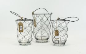 Three Glass And Wire Storm/Garden Lanterns Glass of plain form in descending size order with black