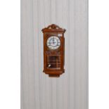 Light Wood Wall Mounted Clock Carved detail to casing, glazed front and sides to expose mechanism.