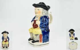 Early 19th Century Period Ralph Wood Type Toby Jug, seated, wearing a black hat, blue coat and