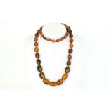 Long Amber Style Necklace, graduating oval beads of a reconstituted resin or similar composition,