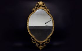 Ornate Reproduction Mirror Baroque style oval mirror in yellow gilt moulded frame with scroll and