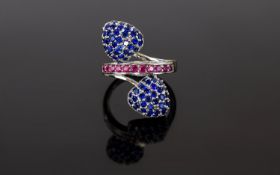 Sapphire and Ruby Cluster Crossover Ring, small blue sapphires set as two domed trillions,