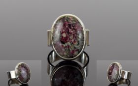 Russian Eudialyte Ring, a 12ct oval cut solitaire eudialyte, bezel set in a silver mount,