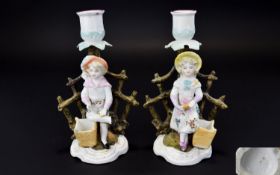 Pair of German Figural Candlesticks and Match Holders, a girl and a boy, each standing in front of a