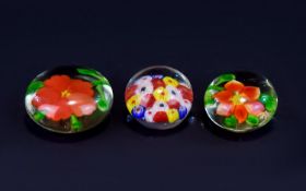 A Collection Of Paperweights Three circular glass paperweights each with encapsulated floral detail.