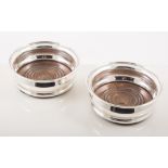 A pair of silver bottle coasters and one other, two wine coasters, various designs,