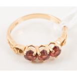 A three stone dress ring, three untested faceted heart shape red stones,