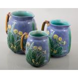A set of three Wedgwood Majolica style graduated jugs, moulded in relief with primulas,