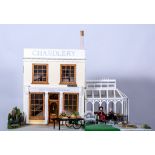 Dolls house of a shop front with greenhouse, quantity furniture and models, 48cm wide, 32cm deep,