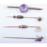 Three stick pins and an amethyst bar brooch,