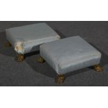 A pair of French sky blue sateen foot stools, late 19th century, on gilt metal lion paw feet,