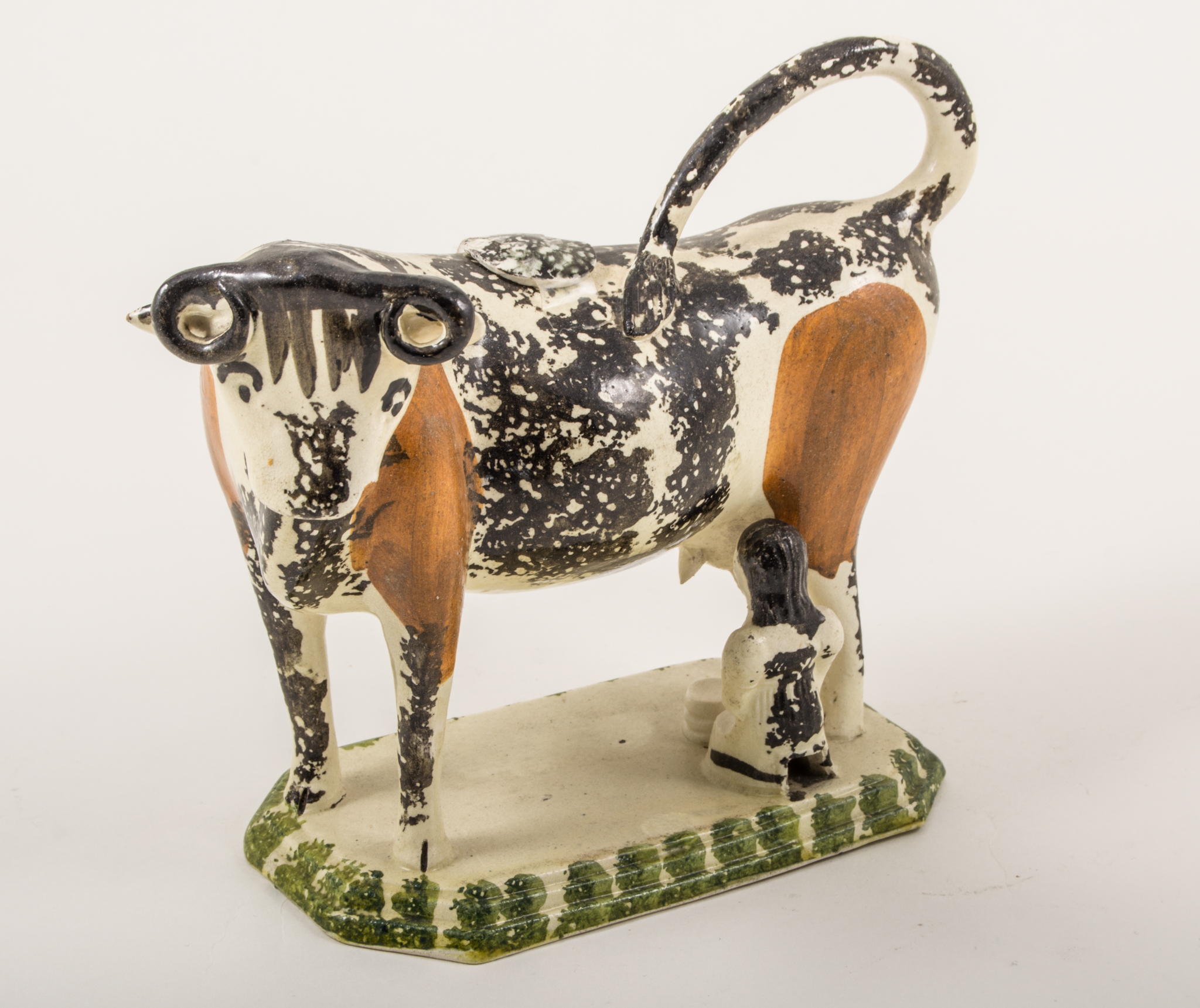 A Creamware type cow and milkmaid creamer, probably Yorkshire, 1800-1820, sponged in black,