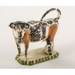 A Creamware type cow and milkmaid creamer, probably Yorkshire, 1800-1820, sponged in black,