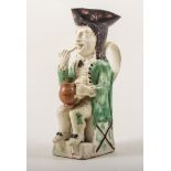 A Ralph Wood type Toby jug, Staffordshire, probably late 18th century, a slender figure seated,