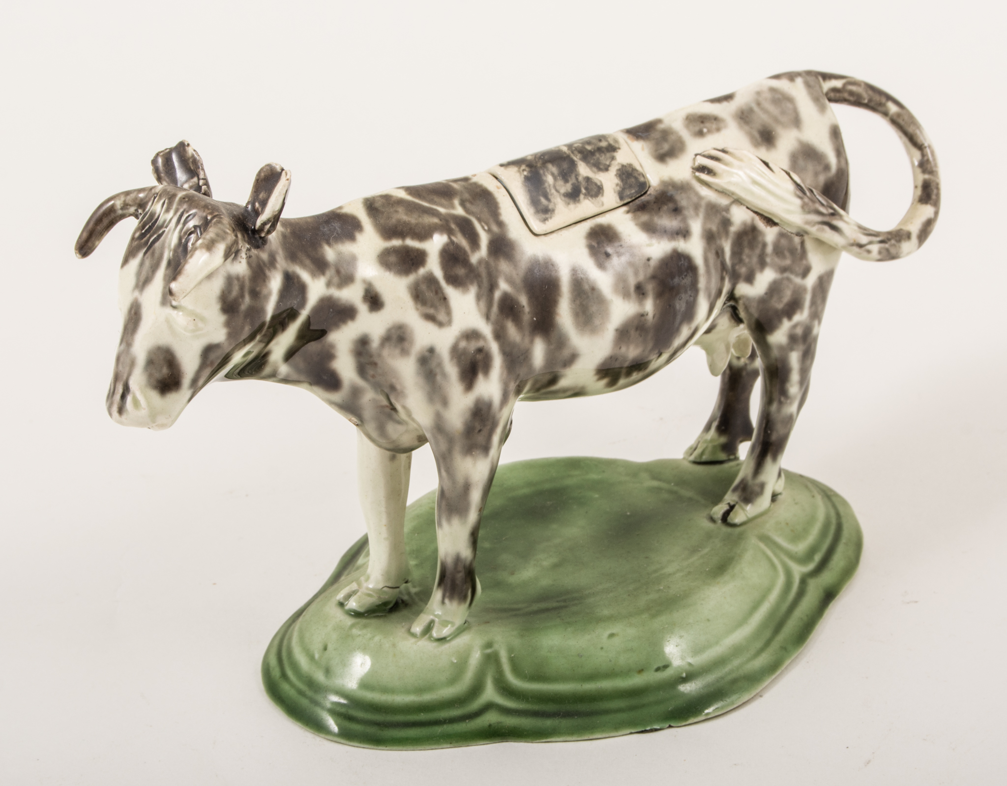 A Pearlware type cow creamer, circa 1800, mottled black, moulded and domed lozenge-shape platform,