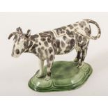 A Pearlware type cow creamer, circa 1800, mottled black, moulded and domed lozenge-shape platform,