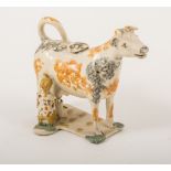 A Creamware type cow and milkmaid creamer, North-East region, 1800-1820, sponged decoration in grey,