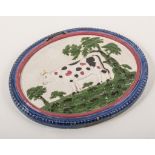 An earthenware cow in a landscape oval plaque, circa 1820, beaded and moulded surround,