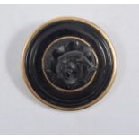 A circular carved rose brooch, untested jet material, 28mm diameter,