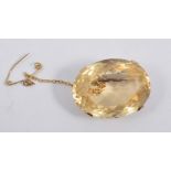 An citrine brooch, the oval mixed cut stone, 30mm x 22mm, four claw set in a yellow metal frame.