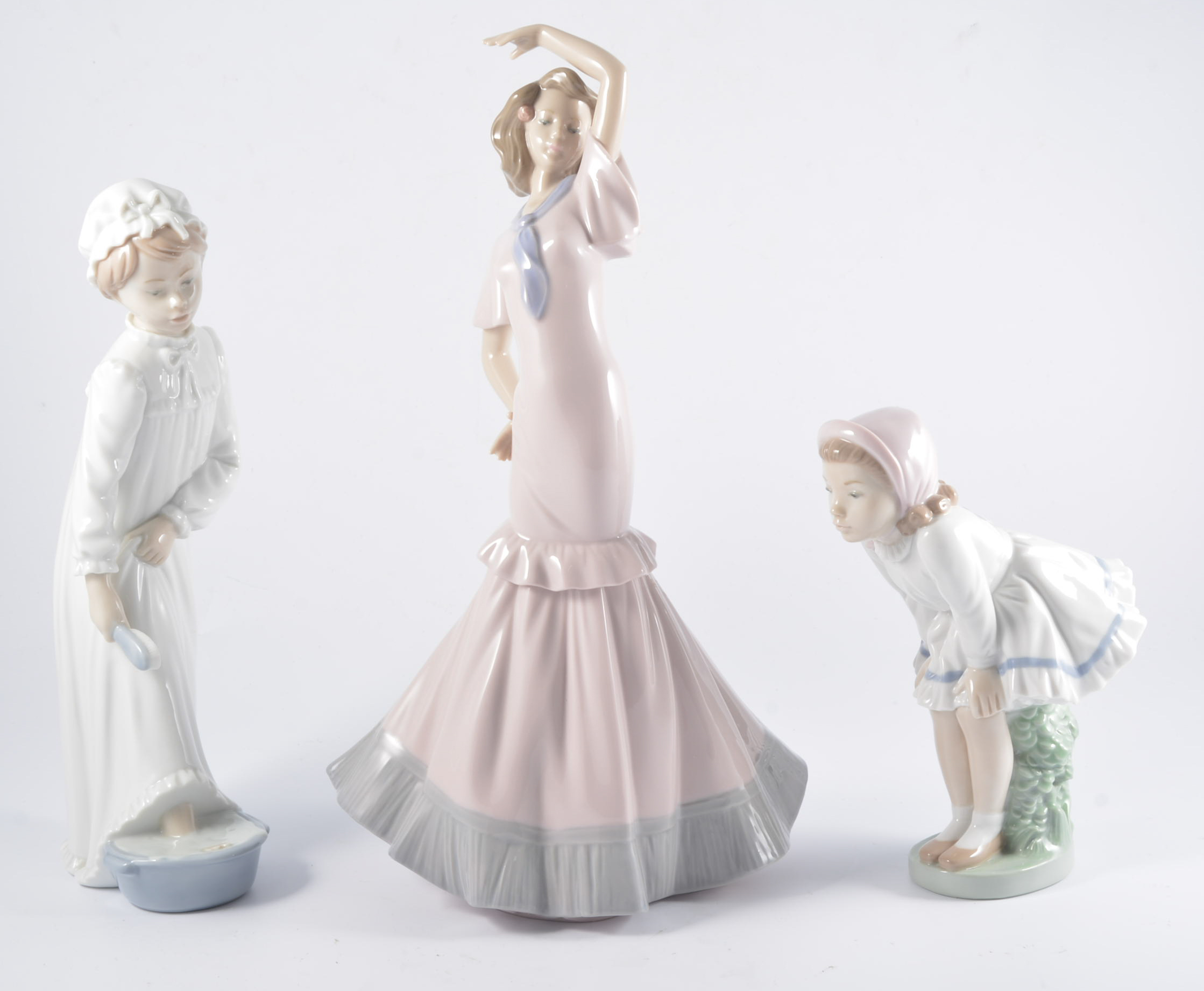 Lladro model, two nuns, No.4611, 33cm, chipped hat; and seven Nao porcelain figures of girls.