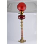 Brass oil lamp, marble column, ruby glass reservoir with a red tinted shade complete with chimney,