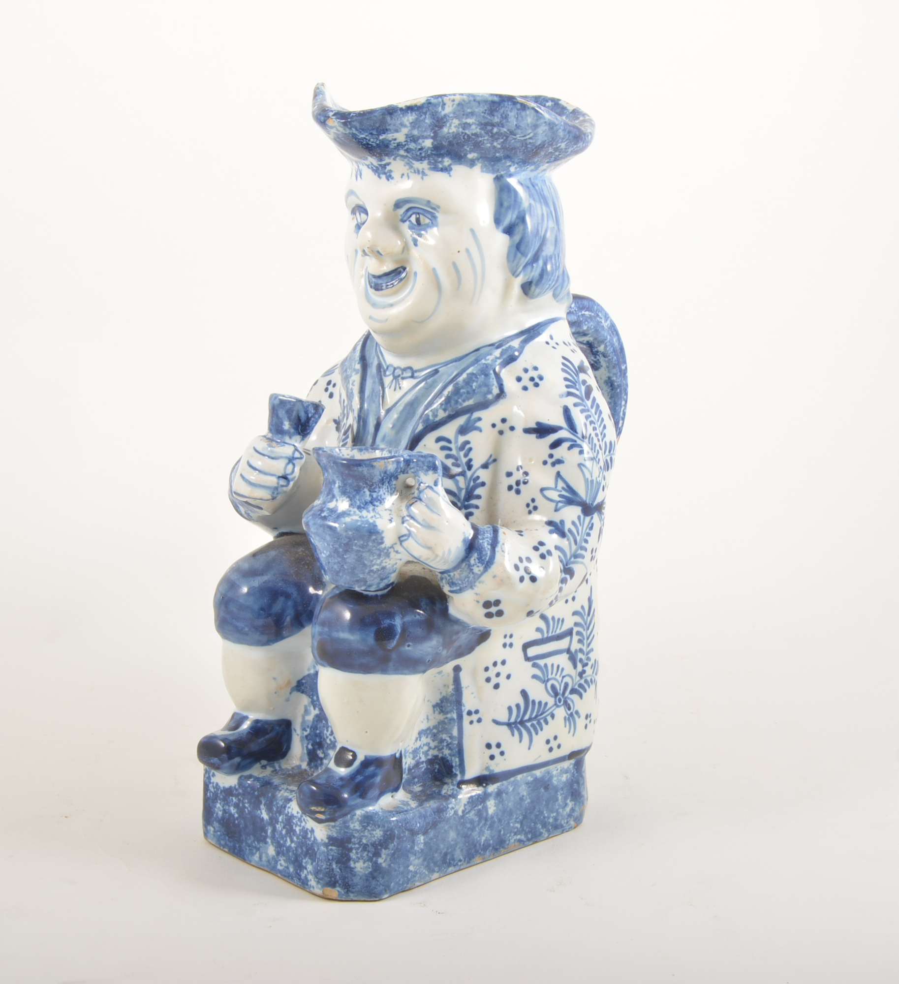 Delft Toby jug, modelled as Mr Toby, seated holding a quart and glass,