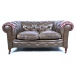 Chesterfield two seater settee, upholstered in brown leather, (heavily worn) raised on bracket feet,