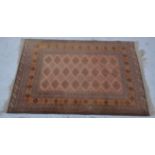 Small Afghan rug, pale red ground with lozenge tiles, stylised floral border, 175cm x 120cm.