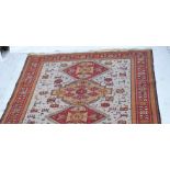 Persian pattern small carpet, five lozenge medallions on a pale field,