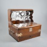 An oak tantalus with silver plated mounts and handles, triple bottle holder, two bottles present,