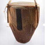 A hide covered tribal drum, with strap, diameter 37cm, height 47cm.