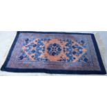 Chinese deep pile wool rug, stylised floral decoration on salmon coloured field, outlined in blue,