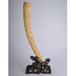 Cantonese fully carved ivory tusk, decorated with dragons on a hardwood flowering prunus stand,