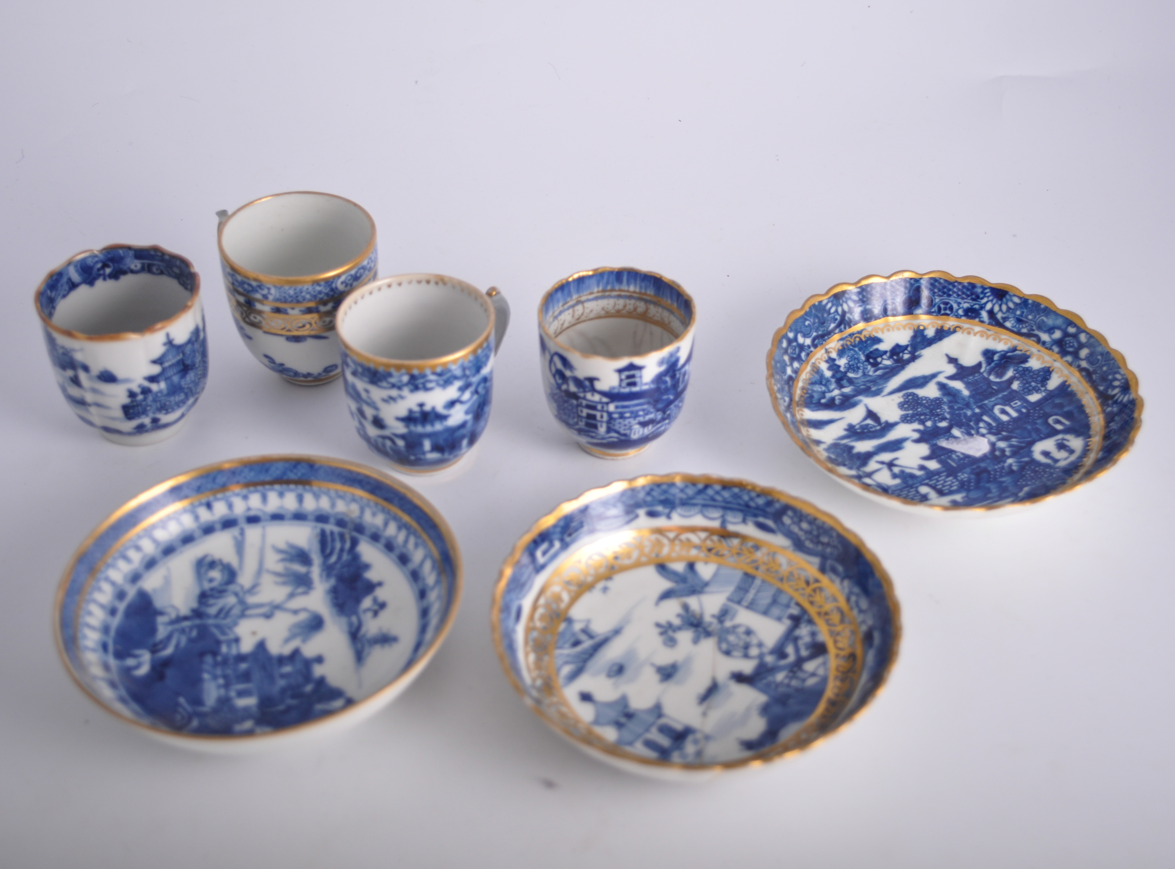 Collection of blue and white tea bowls and saucers, mostly with gilt outlines.