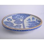 Japanese blue and white dished circular charger, decorated with flowers and a landscape panel,